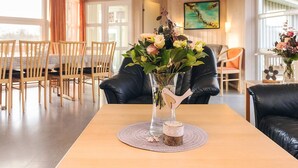 A dining area with a wooden table, chairs, and a vase of flowers. - 4 Star Holiday Home in Ottendorf (Otterndorf)