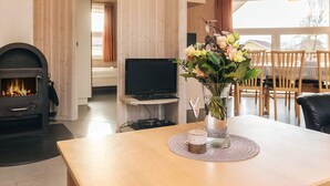 A cozy living room with a fireplace, a television, and a dining area with wooden furniture. - 4 Star Holiday Home in Ottendorf (Otterndorf)