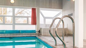 A swimming pool with metal steps leading into it, large windows, and a view of trees outside. - 4 Star Holiday Home in Ottendorf (Otterndorf)