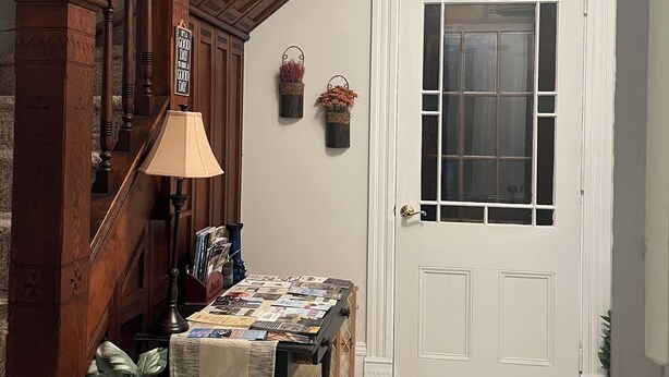 Eine Holztreppe mit einer Lampe, einem Tisch mit Zeitschriften, einer Topfpflanze und einer Tür mit Fenster.