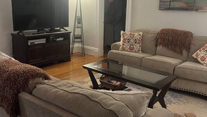 Ein Wohnzimmer mit Flachbildfernseher, Couch, Couchtisch und einem Gemälde an der Wand.