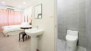 A hotel room with a bed, a round table, a sink, and a shower area. - CASA Yaowarat (Bangkok)