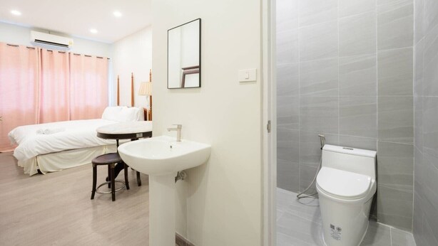 A hotel room with a bed, a round table, a sink, and a shower area. - CASA Yaowarat (Bangkok)