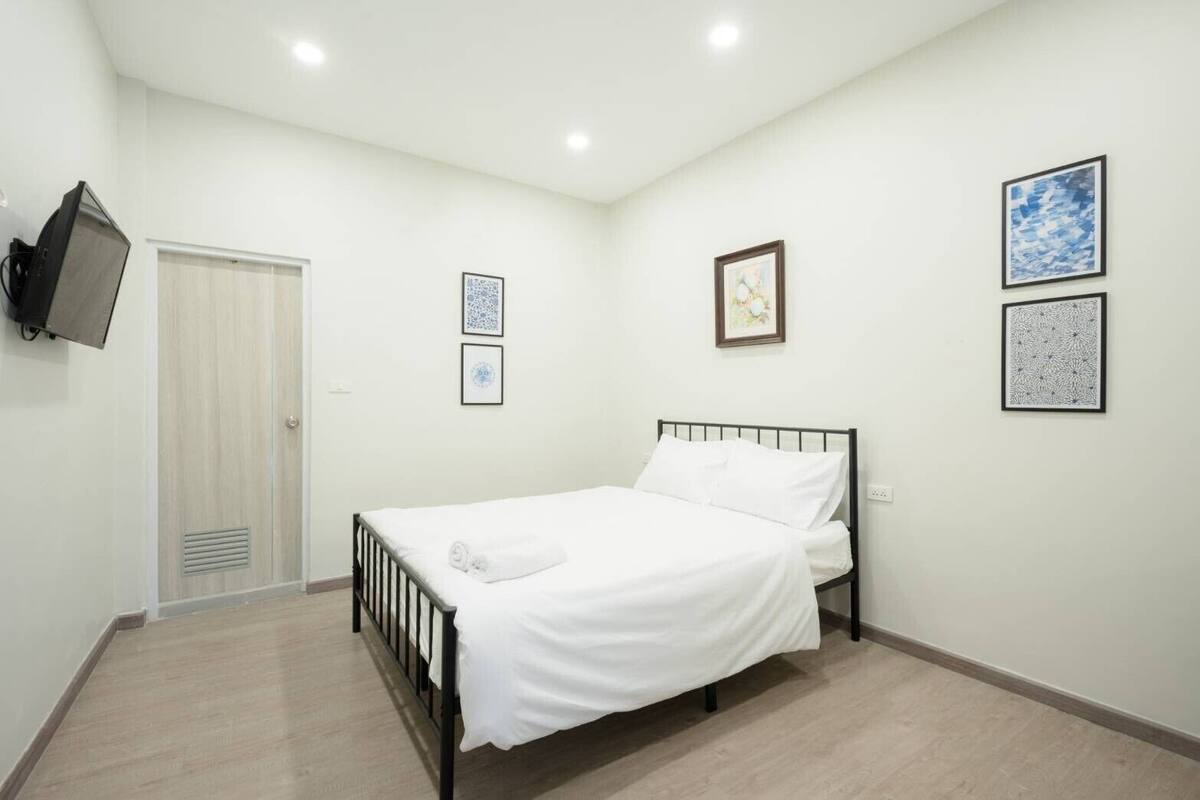 Een slaapkamer met een bed, een kledingkast, een televisie en kunstwerken in lijsten aan de muren.