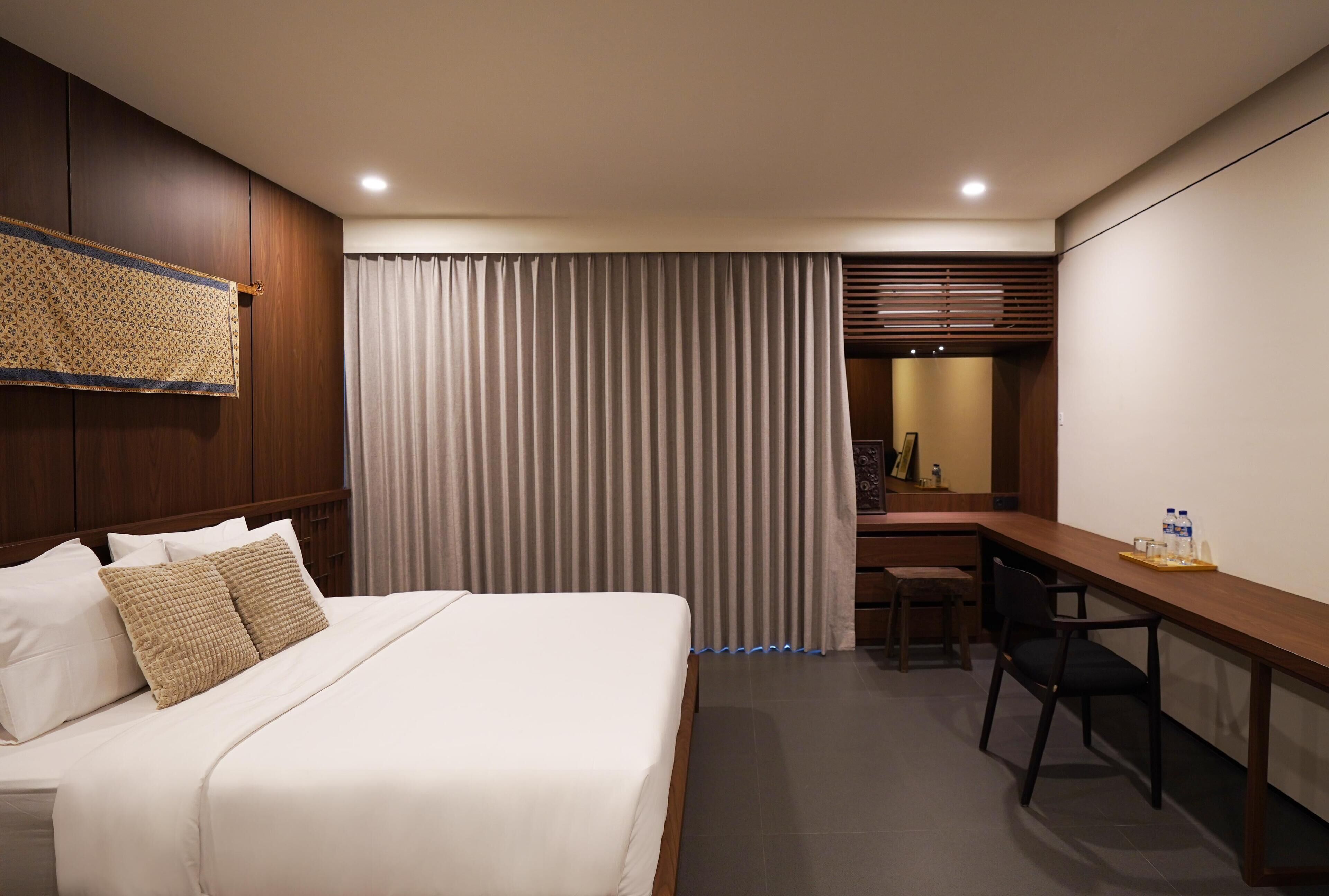 Une chambre d’hôtel avec un grand lit, un bureau et une chaise.