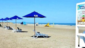 A beach with white lounge chairs and blue umbrellas. - Apt close to the Sea, Historic Center and Las Americas. (Cartagena)