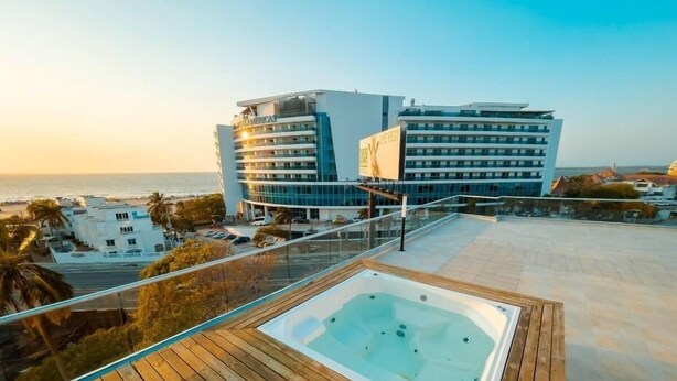 A modern hotel with a rooftop pool area, a view of the ocean, and a large building in the background. - Apt close to the Sea, Historic Center and Las Americas. (Cartagena)