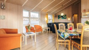 A cozy room with a wooden ceiling, a sofa, a dining table with chairs, and a fireplace. - 4 Star Holiday Home in Ottendorf (Otterndorf)