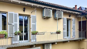 Un immeuble doté de plusieurs unités de climatisation, de volets blancs et de plantes en pot sur le balcon.