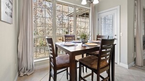 A dining area with a large window, a chandelier, and a table set for four.