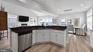 Una cocina amplia con una isla grande, armarios blancos y una lámpara moderna.