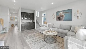 Una sala de estar moderna con un sofá gris, una mesa de centro y una cocina al fondo.
