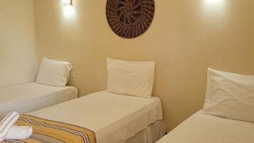 Quarto de hotel com duas camas de solteiro, um ornamento circular na parede e duas luzes fixadas na parede.
