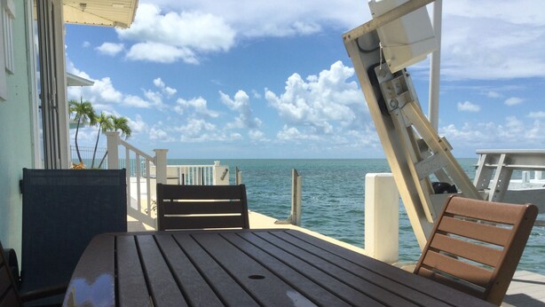 A wooden table and chairs on a deck with a view of the ocean. - Open Ocean View, Private Hot Tub, Ice Machine, Moor 26' Boat! (Marathon)