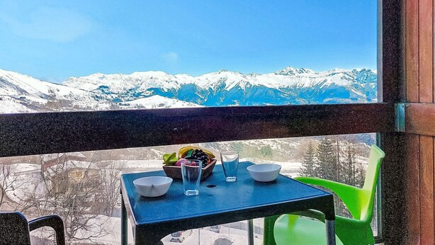 Ein Tisch mit Schalen und einem Glas vor verschneiter Bergkulisse.