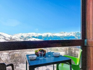 Une table avec des bols et un verre, placée devant un paysage de montagne enneigé.