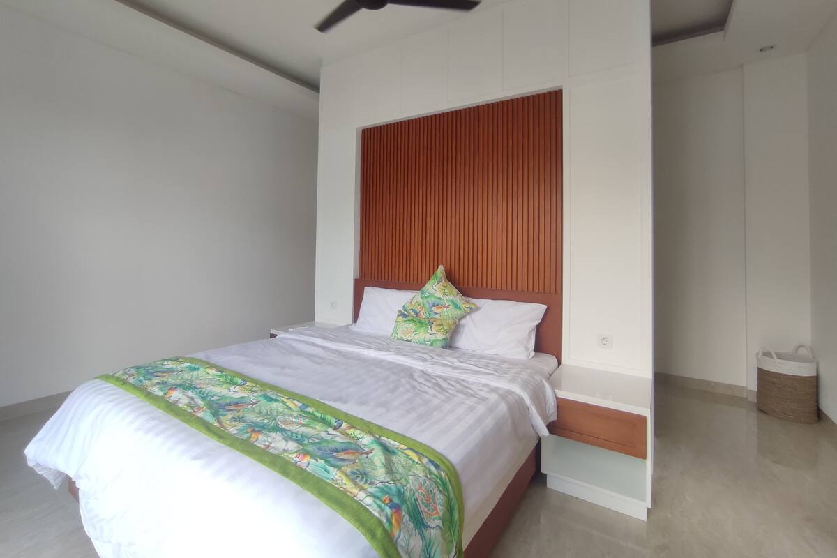 Ein modernes Schlafzimmer mit Bett, Deckenventilator und Holz-Kopfteil.