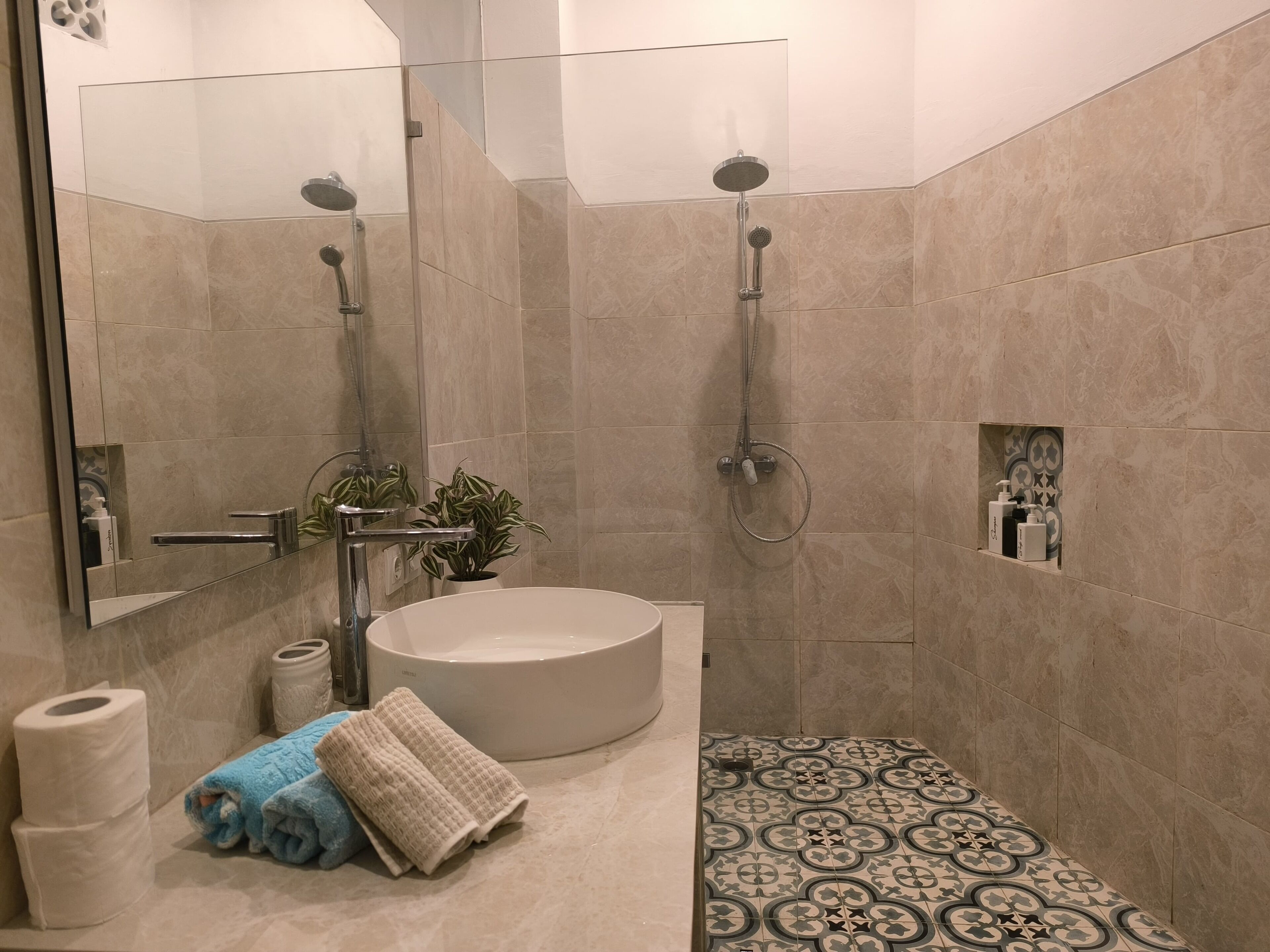 Ein modernes Badezimmer mit einer großen Badewanne, einer Dusche mit Duschbrause und einem Spiegel mit integriertem Ablagefach.