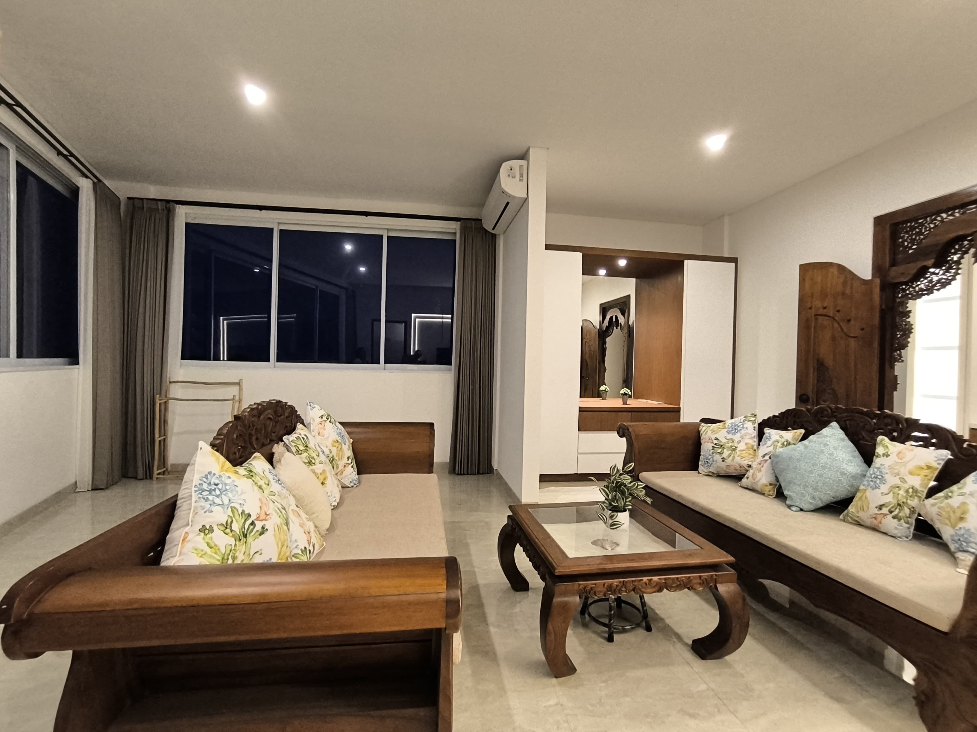 A modern living room with a sofa set, a coffee table, and a large window with curtains.