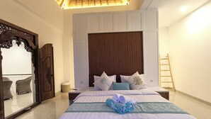 Ein Hotelzimmer mit einem großen Bett, einem Holzkopfstück, einem Spiegel und einer Wandleiter.