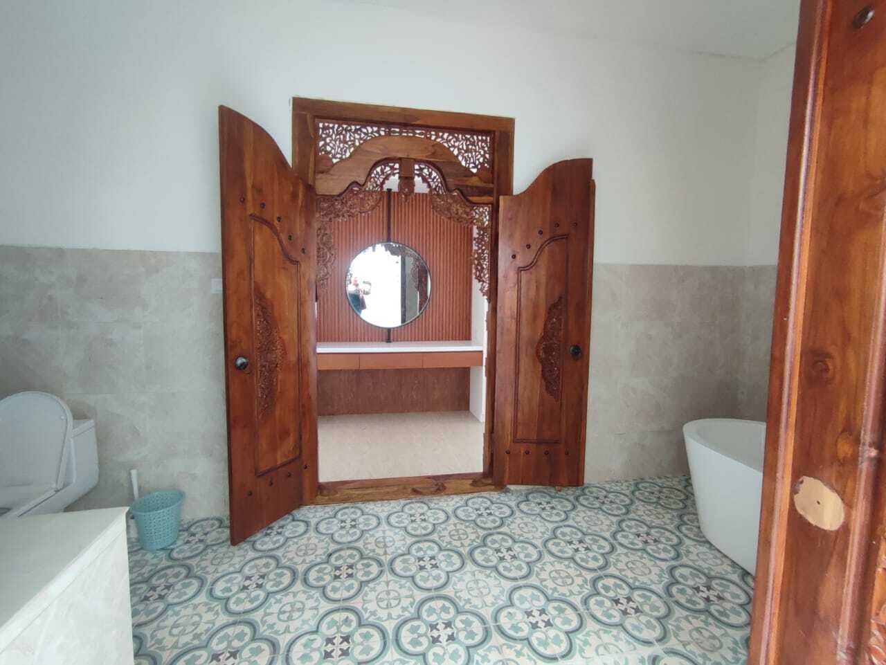 A bathroom with a wooden vanity, a mirror, and patterned floor tiles.