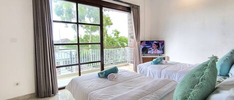 Habitación de hotel con dos camas, televisión y balcón con barandilla.