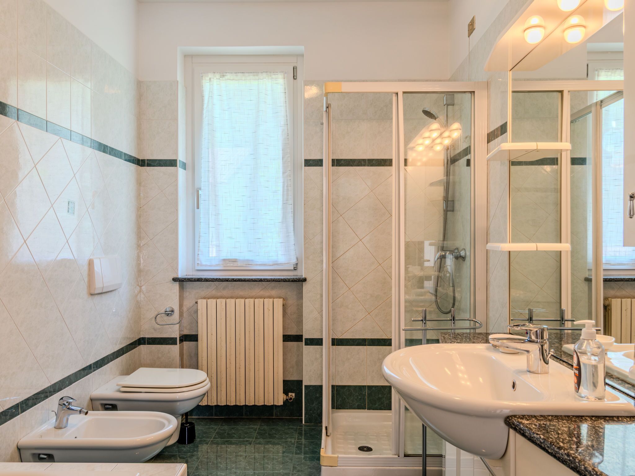 A modern bathroom with a shower, toilet, bidet, and sink.