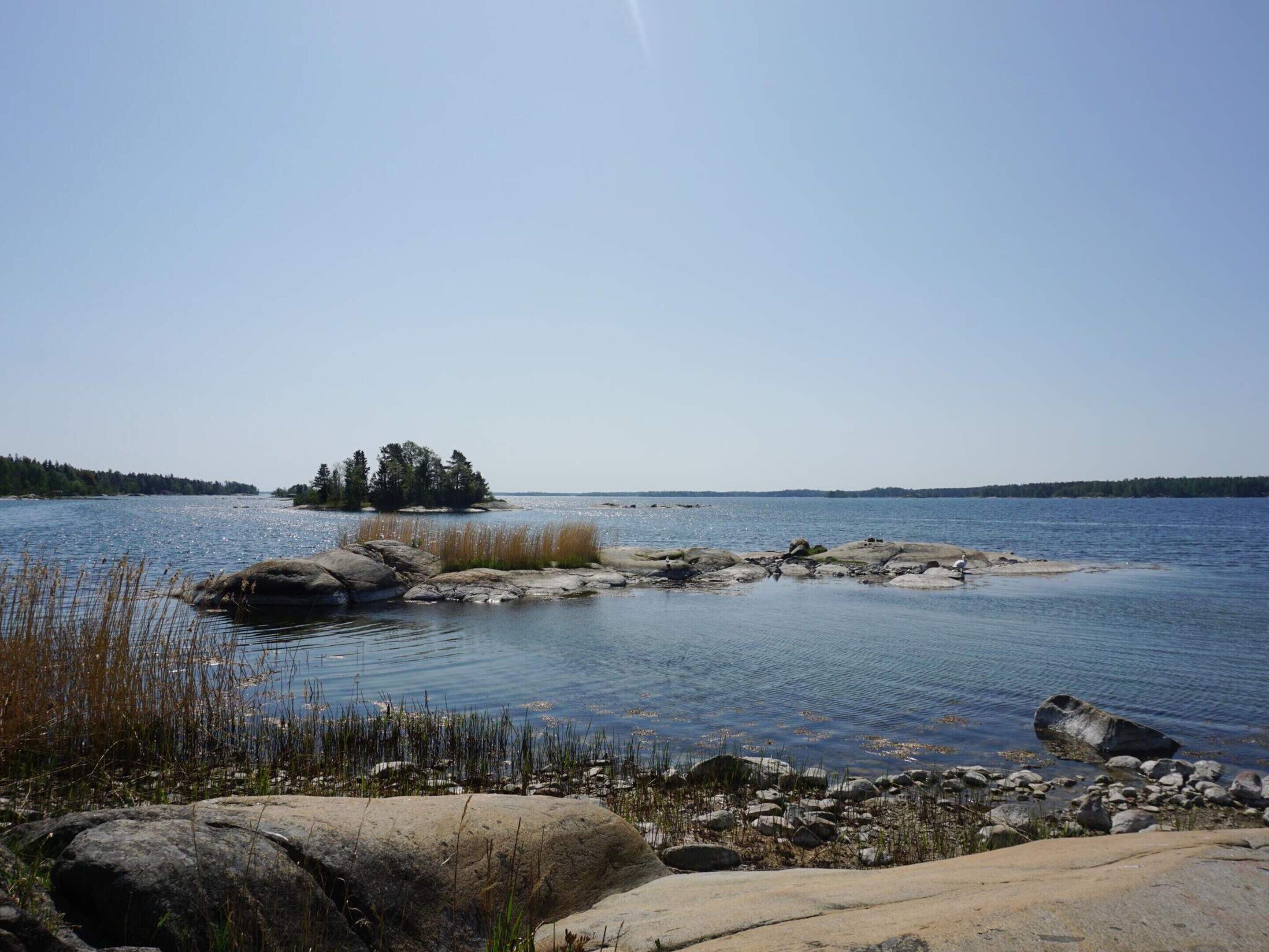 Un lac paisible, bordé d’une rive rocheuse, avec une petite île qui se profile à l’horizon.