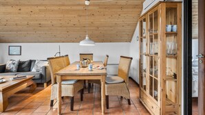A cozy dining area with a wooden table and chairs, a hanging light fixture, and a cabinet with glass doors.