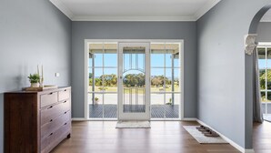 Ein Zimmer mit einem hölzernen Schminktisch, einer großen Glastür, die nach draußen führt, und Blick auf einen Park.