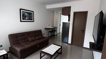 A modern living room with a brown sofa, a coffee table, a TV, and a framed picture on the wall.