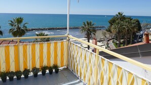 A balcony with a view of the sea, palm trees, and a rocky breakwater. - Casa della Mamma by Interhome (Riva Ligure)