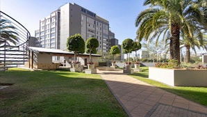 Un patio con un sendero, palmeras y un edificio de varios pisos.
