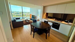 Een modern appartement met een eethoek, keuken en een groot raam met uitzicht op de stad.
