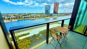 A balcony with a view of a marina, modern buildings, and a river.