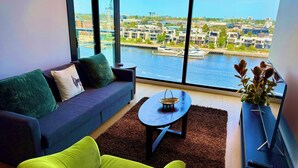 Een moderne woonkamer met uitzicht op een jachthaven en stadsgezicht.