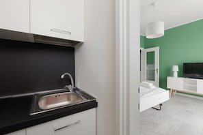 A modern bathroom with a white sink, mirror, and white cabinet.