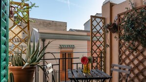 Ein Balkon mit Tisch und Stühlen, Blumentöpfen und einem Holzzaun.