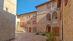 Una calle estrecha con edificios históricos, un sendero adoquinado y un cielo azul despejado.