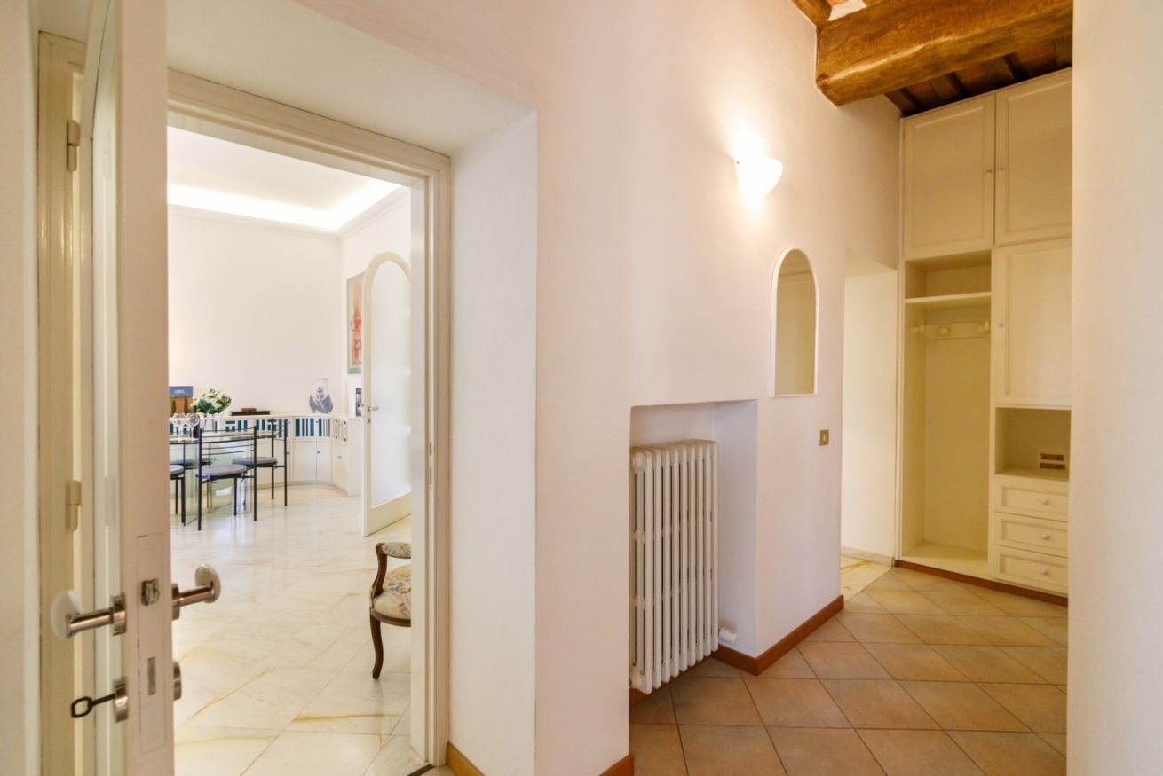 An interior hallway with a white radiator, a wooden ceiling, and a white door leading to a dining area.