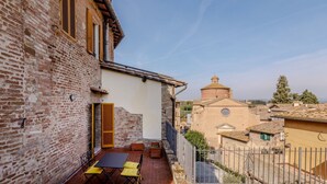 Un patio con una mesa y sillas, un edificio de ladrillo y una iglesia al fondo.