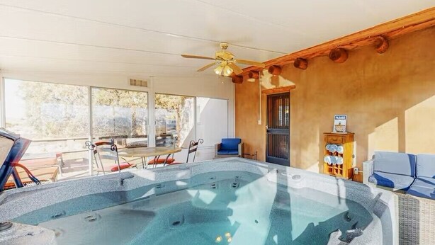 Ein Whirlpoolbereich mit Deckenventilator, Holzwänden und Blick auf Bäume.