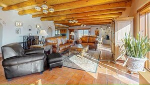 Ein geräumiges Wohnzimmer mit Ledersofas, einem Couchtisch und einer Holzbalkendecke.