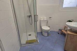 Baño con cabina de ducha de vidrio, inodoro y lavamanos.