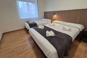 Ein Hotelzimmer mit zwei Betten, einem Holzkopfteil, einer Nachttischlampe und einem Fenster mit Blick.