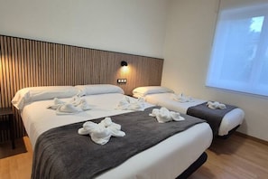 Habitación de hotel con dos camas, cabecero de madera, luz de pared y una ventana.