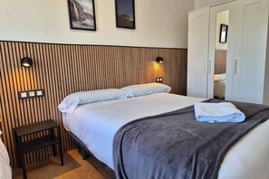 Une chambre d’hôtel comprenant un lit, des tables de chevet, une armoire et des lampes fixées au mur.