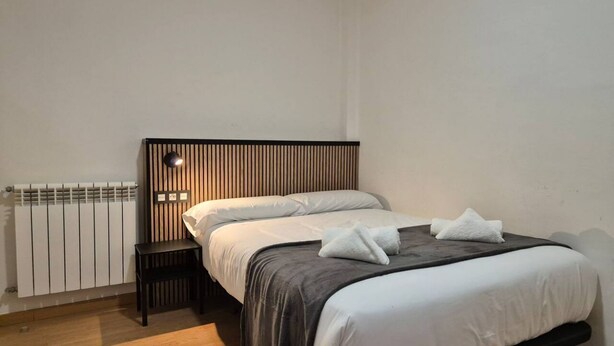 Ein Schlafzimmer mit Bett, Nachttisch und Wandleuchte.
