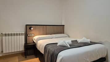 A bedroom with a bed, bedside table, and a wall-mounted light.