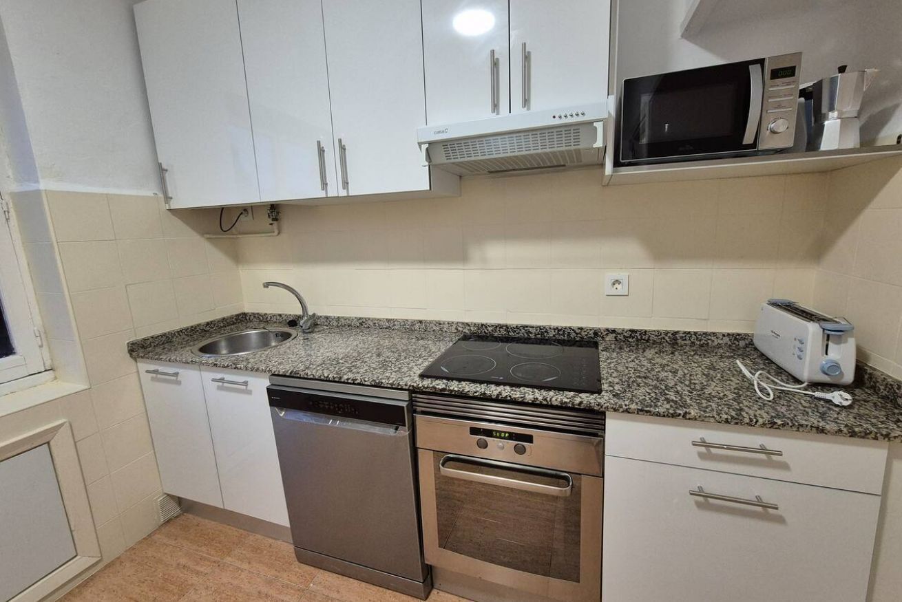 A compact kitchen with white cabinets, a dishwasher, an oven, a microwave, and a toaster.